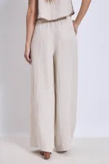 Conjunto de lino color beige, compuesto por un top sin mangas con cuello halter y un pantalón palazzo de tiro alto con cintura elastizada.