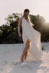 Vestido largo de color blanco, con escote en V pronunciado y tiras largas que permiten anudarlo de múltiples formas. Presenta tajo en ambos laterales y forro interno.