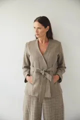 Chaqueta corta entallada color beige, con escote en V, manga larga, cierre frontal con lazo fijo y bolsillos escondidos. Confeccionada en lana fina sin teñir, diseñada exclusivamente por Don Baez.
