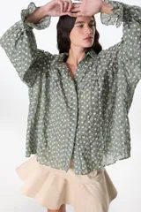 Camisa celeste a rayas verticales blancas, con cuello clásico, cierre frontal con botones y mangas largas abullonadas con puños elásticos.