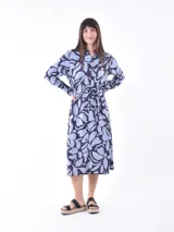 Vestido midi camisero con estampado abstracto en tonos celeste y azul marino. Tiene cuello camisero, mangas largas y lazo en la cintura.