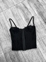 Corset negro de encaje con copas preformadas, breteles finos regulables y cierre frontal con ganchos.