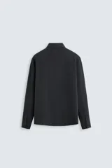 Camisa negra de corte relaxed fit confeccionada en tejido fluido con mezcla de viscosa. Tiene cuello solapa, manga larga con puño abotonado y cierre frontal con botones.