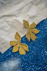 Par de aros con forma de flor roja brillante y detalle de strass plateado en el centro. Cierre a presión de acero inoxidable.