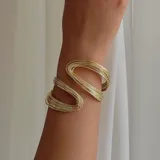 Brazalete dorado rígido, con diseño abierto y forma ondulada.