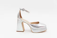 Zapato de tacón plateado de cuero, con plataforma, pulsera al tobillo y hebilla redonda.