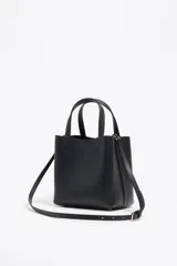 Bolso tote pequeño de cuero sintético color negro con doble asa de mano y correa bandolera ajustable y extraíble. Logotipo de la marca en letras doradas en la parte frontal.