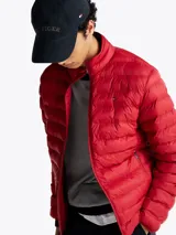 Campera acolchada roja de Tommy Hilfiger, con cuello alto y cierre de cremallera. Cuenta con dos bolsillos laterales con cremallera y logo bordado en el pecho.