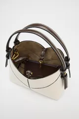 Bolso mini shopper de tejido canvas color crudo con pespuntes en contraste negro. Tiene asas de mano y correa bandolera extraíble. Incluye cartera interior con cremallera dorada.