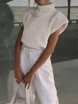 Chaleco de punto color crema, con cuello alto y corte holgado.