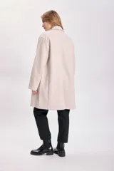 Tapado beige de corte recto con cuello solapa y cierre con un botón.
