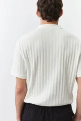 Remera polo blanca de punto texturizado de peso medio. Modelo de manga corta con cuello, tapeta de botones y bajo recto. Corte ajustado que realza el contorno del cuerpo creando una silueta entallada.