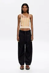 Pantalón blanco de lino y algodón, corte barrel, largo tobillero, con cierre frontal oculto, bolsillos delanteros y traseros, y cinturón de tela a tono.