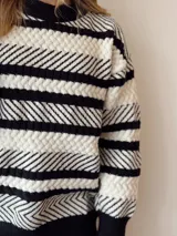 Sweater de punto con rayas horizontales en blanco y negro, cuello redondo y corte holgado.