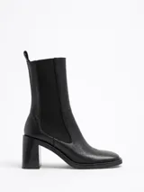 Botín negro de cuero, con punta cuadrada, caña media y elásticos laterales. Taco cuadrado de 7,5 cm.