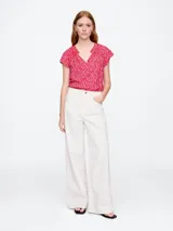 Blusa blanca de manga corta con escote en V y detalle de volados en el cuello.