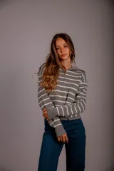 Sweater de punto color beige con rayas horizontales blancas, cuello polo con cierre de cremallera y mangas largas.