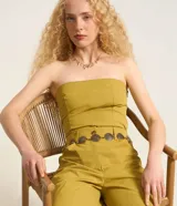 Blusa sin breteles color amarillo mostaza, confeccionada en sarga, con cierre por cremallera invisible en el lateral y bolsillos con solapa en la parte del frente. Posee lastex en la espalda y bajo redondeado.