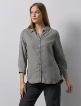 Camisa celeste de tencel con cuello con solapa, escote en V, abertura central con botones y mangas 3/4 regulables con presilla y botón.