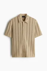 Camisa de manga corta color beige en punto jacquard. Modelo con cuello inglés, tapeta clásica y bajo recto.