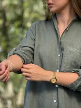 Vestido camisero blanco de lino, con cuello camisero, manga larga con botón para recoger, cierre frontal con botones de nácar, bolsillo en el pecho y diseño asimétrico más largo en la parte trasera.