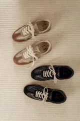 Championes acordonados color beige y dorado con suela marrón.