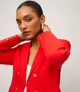 Blazer femenino color rojo, de corte estructurado, con cuello solapa, cierre frontal con botones dorados y bolsillos delanteros.