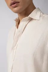 Camisa de manga larga color beige claro, con cuello abierto y calce relajado.