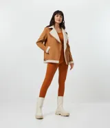 Campera marrón de terciopelo con cuello camisero y forro de sherpa color crema. Tiene cierre frontal con cremallera y bolsillos delanteros con cremallera.