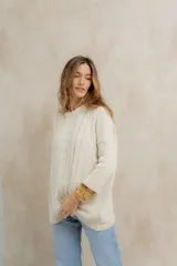 Sweater tejido en hilo de algodón color crudo, con cuello redondo, corte holgado, hombros caídos y diseño de ochos en la parte delantera.