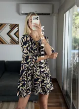 Vestido corto color verde oliva con estampado de hojas en blanco y negro, escote con lazo ajustable y mangas 3/4 acampanadas.