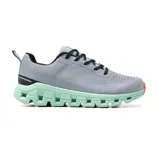 Championes deportivos grises con suela verde agua y detalles en negro y naranja.
