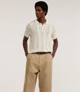 Pantalón masculino estilo sastre, corte balloon (holgado con volumen y talle alto), color beige. Presenta pliegues frontales y cierre tradicional.