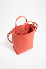 Bolso de mano mediano marca Bimba y Lola, color naranja, confeccionado en cuero con textura granulada. Tiene doble asa corta, correa bandolera ajustable y extraíble, logo estampado en el frente y herrajes plateados. El interior cuenta con etiqueta de tejido con el logo de la marca.