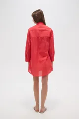 Camisa blanca de algodón con cuello clásico, corte holgado, cierre frontal con botones y mangas largas.