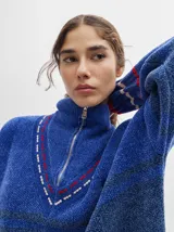Sweater azul con cuello alto con medio cierre, textura tipo terciopelo y puños acanalados.