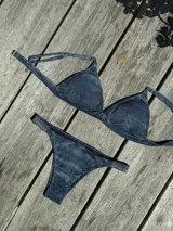 Conjunto de bikini turquesa con corpiño triangular de corte fijo, breteles regulables y almohadillas desmontables, y bombacha vedetina con frunce elástico en los costados.