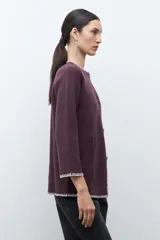 Saco de punto color ciruela oscuro, de manga larga y cuello redondo, con cierre frontal de botones y ribetes en contraste blanco con puntada decorativa.