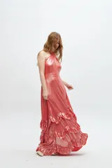 Vestido largo color salmón metalizado con escote halter cruzado y espalda descubierta. Falda larga con volados en capas.
