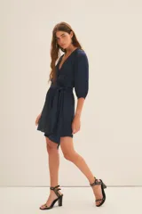 Vestido corto azul marino de manga 3/4, con escote en V cruzado y lazo en la cintura.