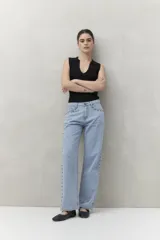 Pantalón jean gris oscuro de corte recto, tiro alto y calce relajado. Presenta apliques metálicos en los laterales.