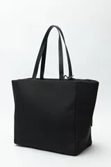 Bolso tote negro de nylon con diseño acolchado, asas largas para llevar al hombro, cierres metálicos laterales y detalle de cordón.