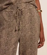Pantalón fluido de cintura alta confeccionado en crepé con elástico y lazo en la cintura, bolsillos, recortes y estampado de lunares diferenciado.