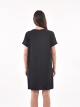 Vestido negro corto de corte recto, con cuello redondo y bolsillo en el pecho.