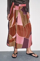 Falda midi de tiro alto confeccionada en hilatura de algodón con estampado geométrico multicolor. Detalle de pliegues en cintura y bajo evasé. Cierre con cremallera oculta en costura.