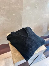 Sweater negro de tejido de punto con escote en V y mangas largas.