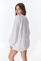 Camisa beige de manga larga con botones y detalles de encaje.