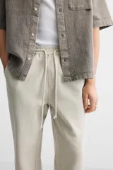Pantalón color arena de corte recto, confeccionado en tejido de algodón y lino. Cuenta con cintura elástica ajustable con cordón, bolsillos delanteros y traseros de parche.