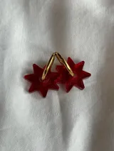 Par de aros dorados con forma de estrella negra.