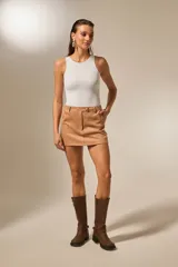 Minifalda de gamuza color camel, de corte recto, con talle alto y cierre frontal con un botón dorado.